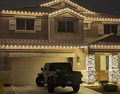 Two-story home with warm white C9 lights tracing both rooflines and two lit columns at the front entry